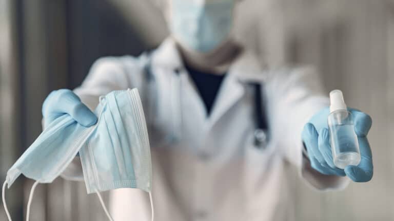 Doutor segurando mascara e álcool gel